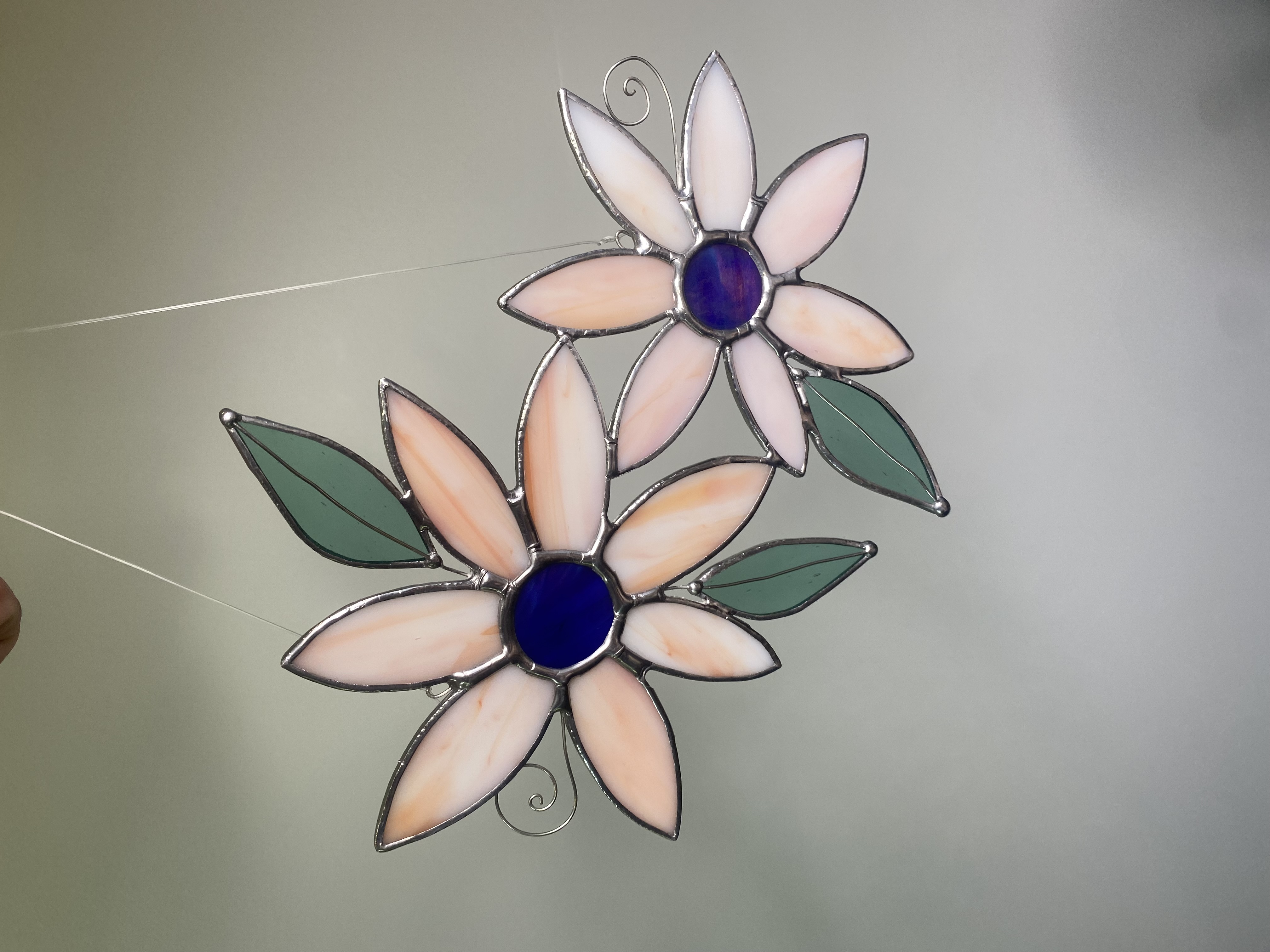 Two flower suncatchers with peach petals and cobalt-blue centers